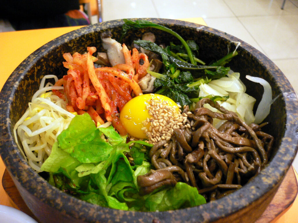 Dolsot bibimbap served sizzling in a heated stone pot, where a crispy nurungji rice crust forms on the bottom. Photo: abex, CC BY-SA 2.0, via Wikimedia Commons