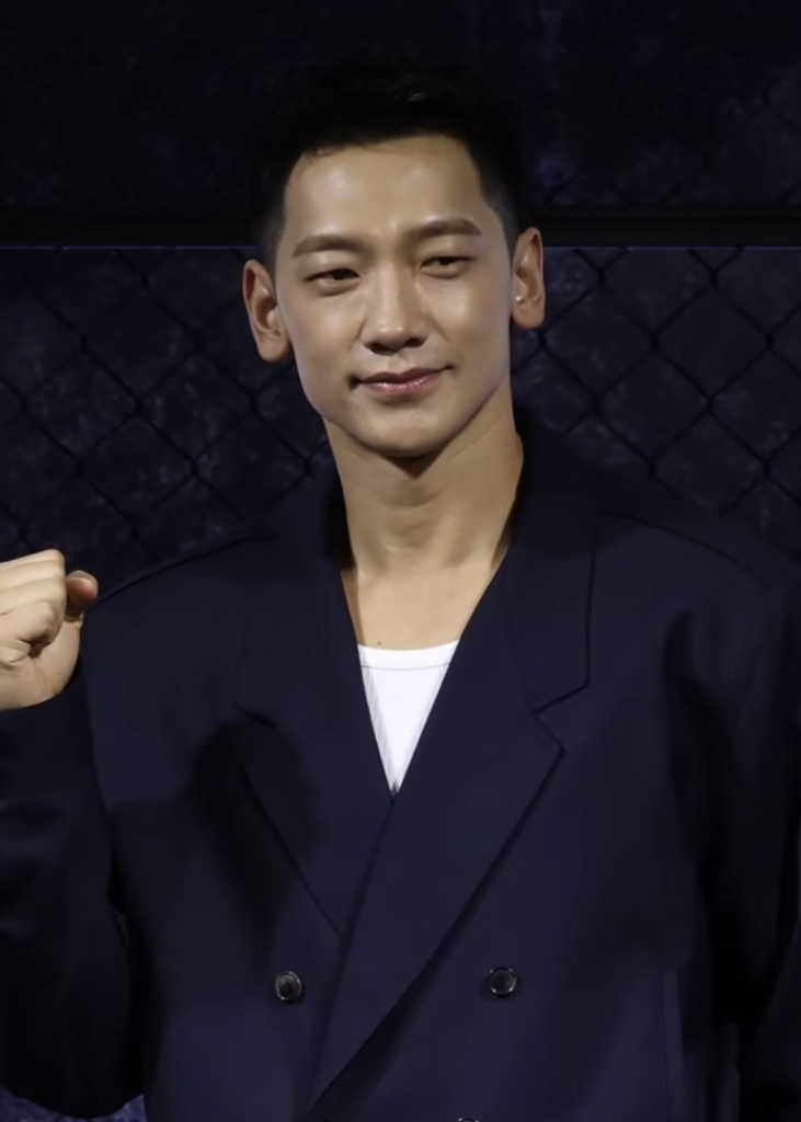 Rain (비 / 정지훈, Jung Ji-hoon), who joins Bloodhounds Season 2 as new villain Im Baek-jeong, at the Bloodhounds 2 press conference in March 2026 (press photo, not a still). (Photo: TV10, CC BY 4.0 via Wikimedia Commons)