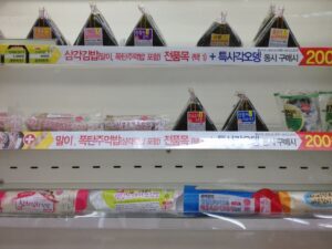 Brightly lit shelves of packaged snacks and drinks inside a small 24-hour Korean convenience store