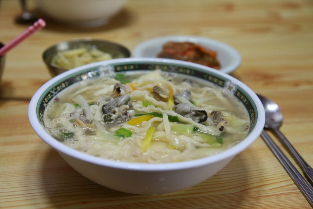 바지락 칼국수 (Bajirak kalguksu) — manila clam knife-cut noodle soup; the signature manila-clam (바지락) dish — a representative photo of the dish, not necessarily from the restaurants above. Photo: Photo by Suh Jeong-ho (Pixabay user daecheonnet), via Wikimedia Commons "File:Bajirak-kalguksu.jpg". License: CC0 1.0 (no attribution legally required).