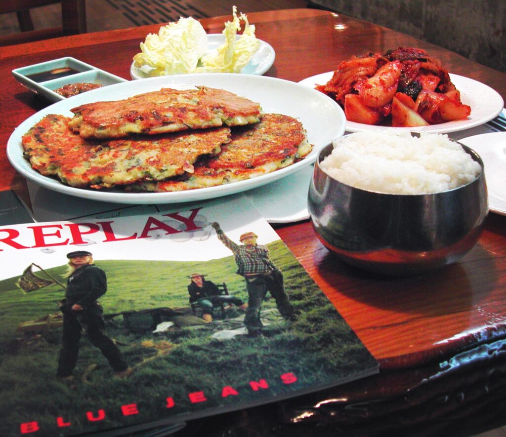빈대떡 (Bindae-tteok / mung-bean pancake) — a representative photo of the dish, not necessarily from the restaurants above. Photo: Photo by moriza (Mo Riza), via Wikimedia Commons, licensed CC BY 2.0 (https://creativecommons.org/licenses/by/2.0). File: Korean pancake-Bindaetteok-01.jpg