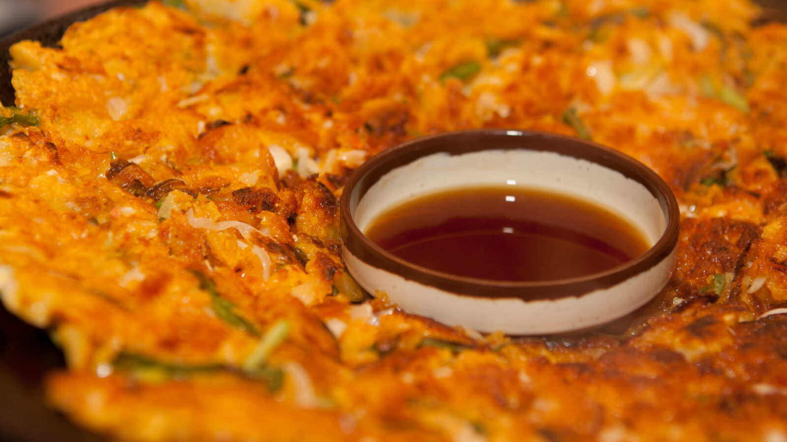 Haemul-pajeon, the Korean seafood and scallion pancake, served whole on a plate.