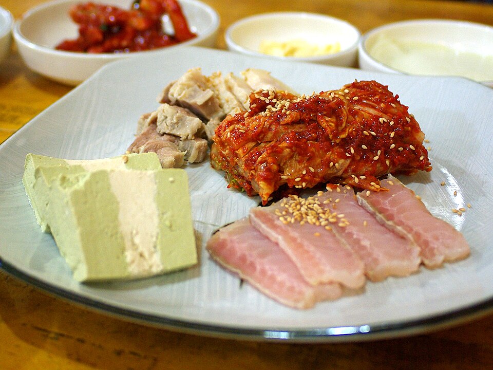 Hongeo-samhap: fermented skate stacked with boiled pork and aged kimchi, the classic 'three-way harmony.' (Photo: egg (Hong, Yun Seon), CC BY 2.0 via Wikimedia Commons)