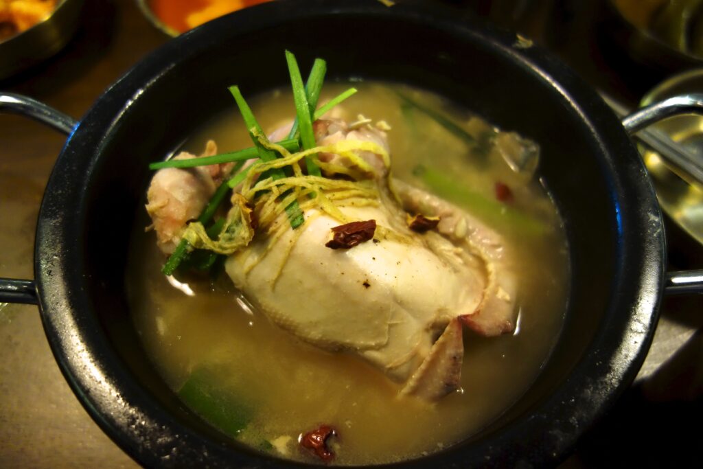 The whole young chicken sits in the ginseng broth, its cavity packed with sweet rice, garlic and jujube.