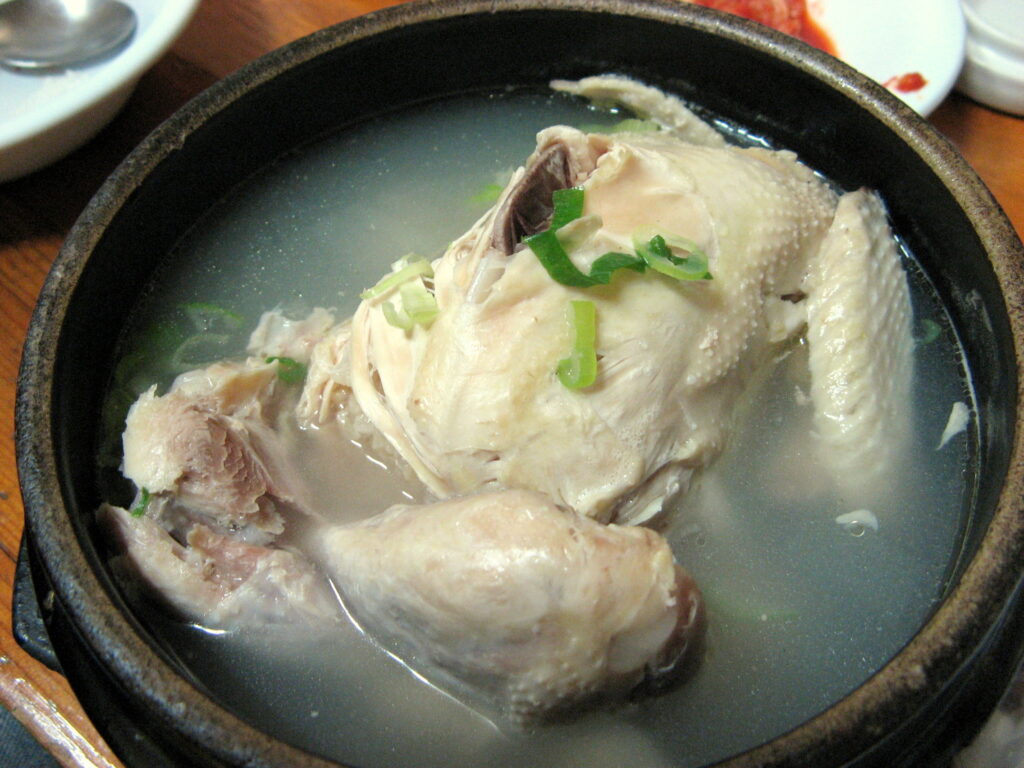 Korean ginseng chicken soup ready to eat — pick the tender meat first, then spoon up the broth-soaked rice from inside.