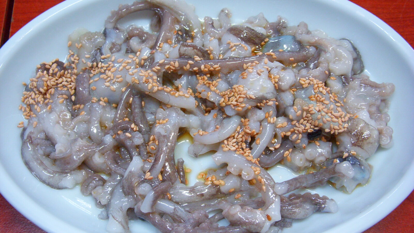 San-nakji (산낙지) hoe — freshly sliced small octopus served Korean-style with sesame seeds, the arms still moving.