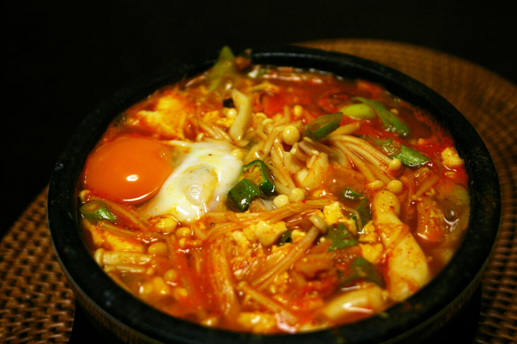 Soft tofu stew served in a traditional earthenware bowl that keeps it searing hot to the last spoonful.