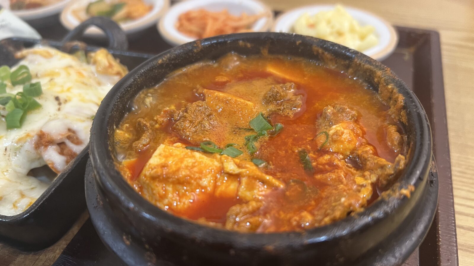 Sundubu-jjigae bubbling in a stone pot, served the classic way next to rice and banchan.