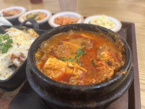 Sundubu-jjigae bubbling in a stone pot, served the classic way next to rice and banchan.